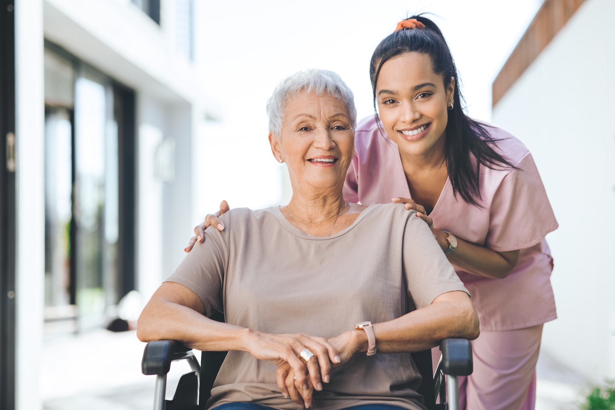 Portrait of a young nurse caring for an older woman in a wheelchair